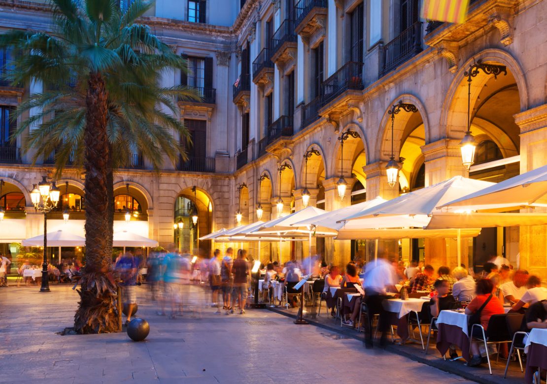 Kveldsutsikt over Plaça Reial med restauranter en sommerkveld i Barcelona.