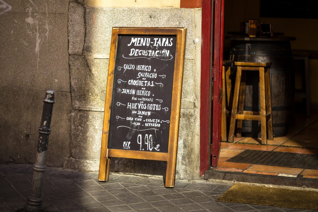Tavle utenfor en restaurant som tilbyr «menú del día» med typiske tapasretter til fast pris.