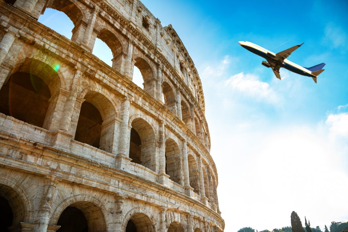 Nærbilde av Colosseum i Roma med et fly i bakgrunnen.
