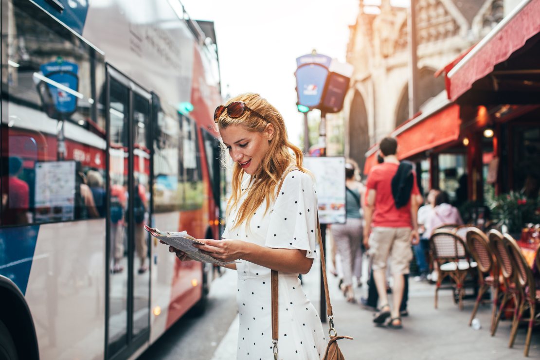 Ung kvinnelig turist planlegger hop-on-hop-off sightseeing i Paris