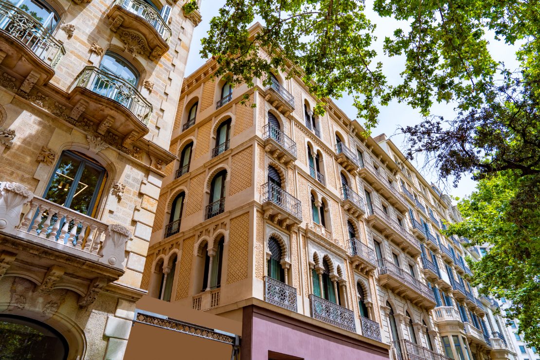 Passeig de Gràcia i Eixample-distriktet i Barcelona sentrum, med livlig arkitektur og trær langs avenyen på en solrik dag.