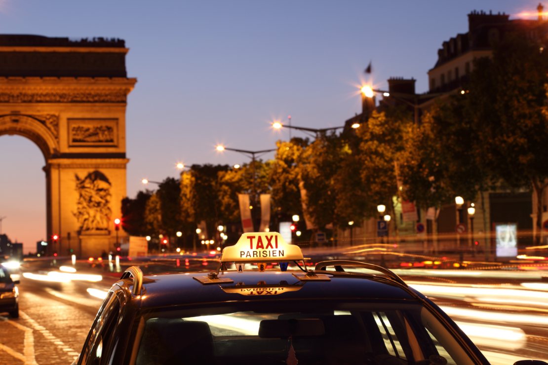 Pariserdrosje med Triumfbuen og lysstriper fra trafikken i bakgrunnen.